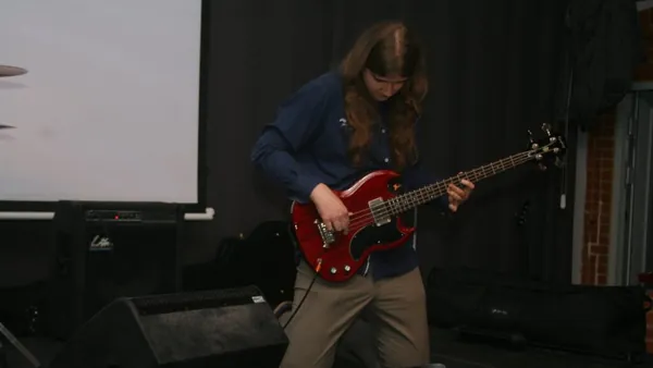 Mateusz Pawelec gra na czerwonej gitarze basowej