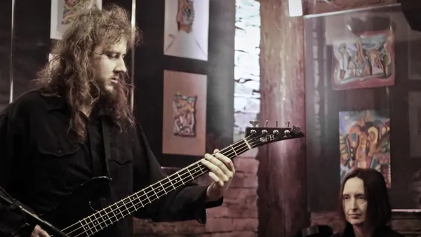 Mateusz Pawelec gra na gitarze basowej w klubie, w tle wokalistka przy klawiszach