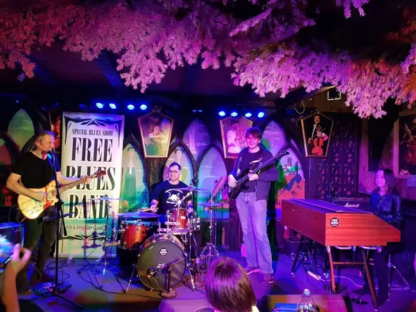 Free Blues Band na scenie z banerem zespołu, w fioletowo-różowym świetle