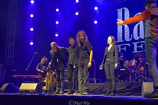 Zespół kłania się publiczności na scenie Rawa Blues Festival w niebieskim świetle