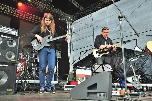 Basista i gitarzysta grają na plenerowej scenie pod namiotem