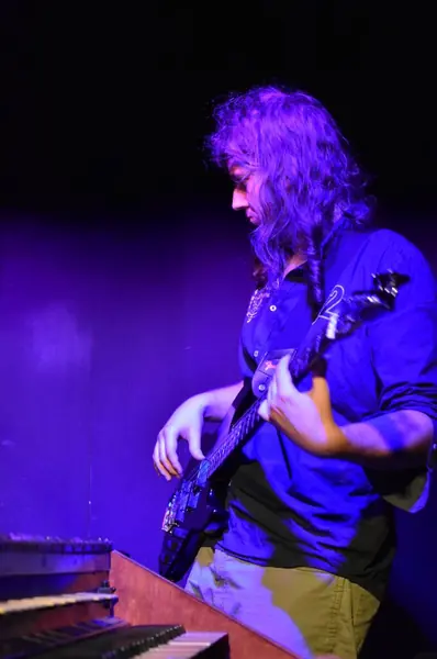 Mateusz Pawelec gra na gitarze basowej w fioletowym świetle