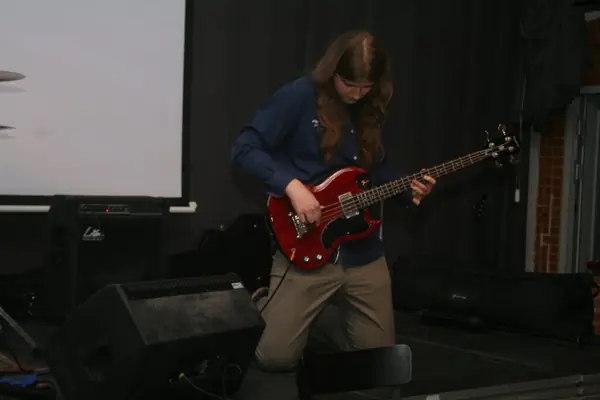 Mateusz Pawelec gra na czerwonej gitarze basowej